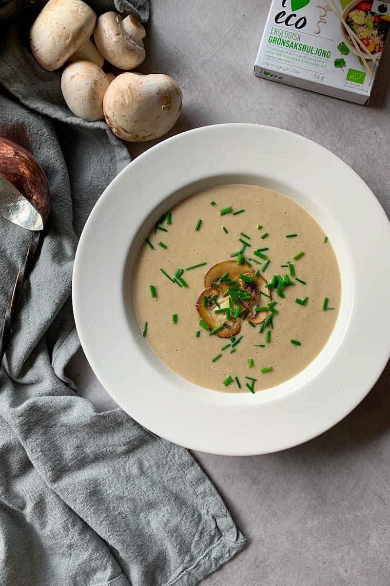 Creamy mushroom soup served with chives and mushroom slices in a white bowl