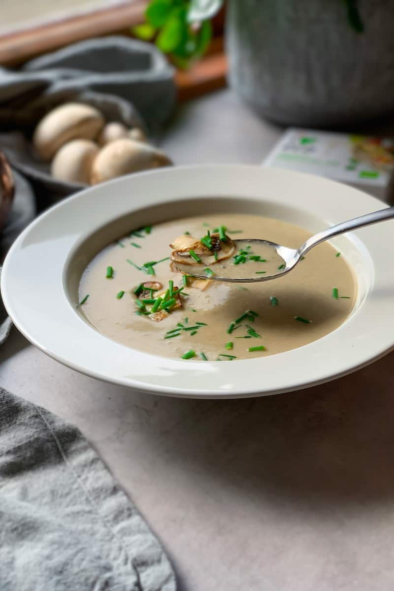 Eating creamy mushroom soup with chives from a white bowl