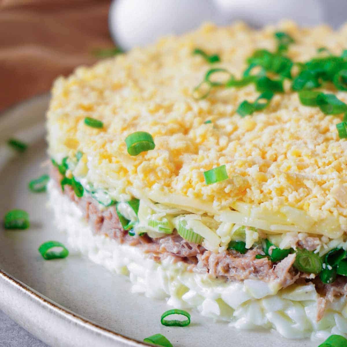Close up picture of keto tuna egg salad layered as a cake and garnished with chopped green onions.