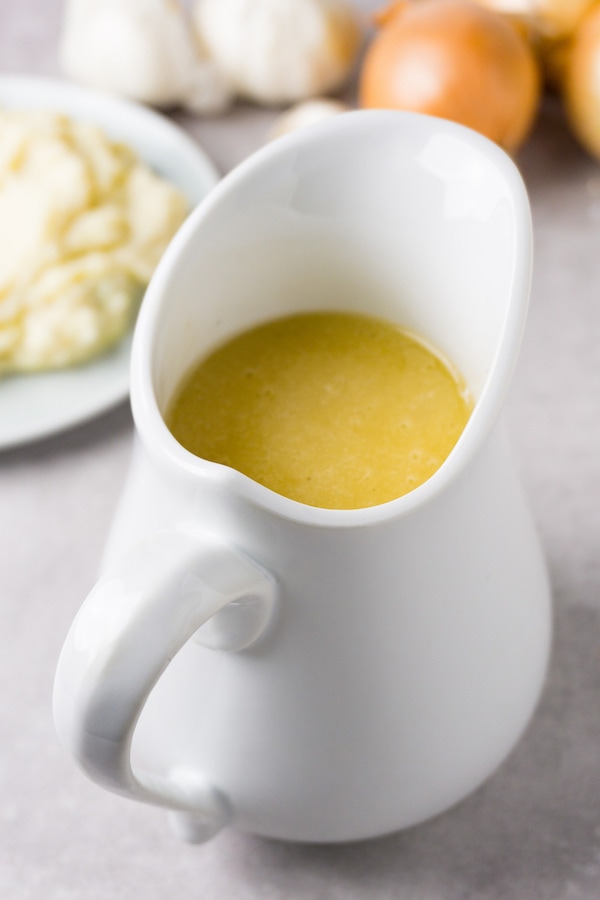 A white sauce jug filled with flourless and gluten-free gravy sauce.