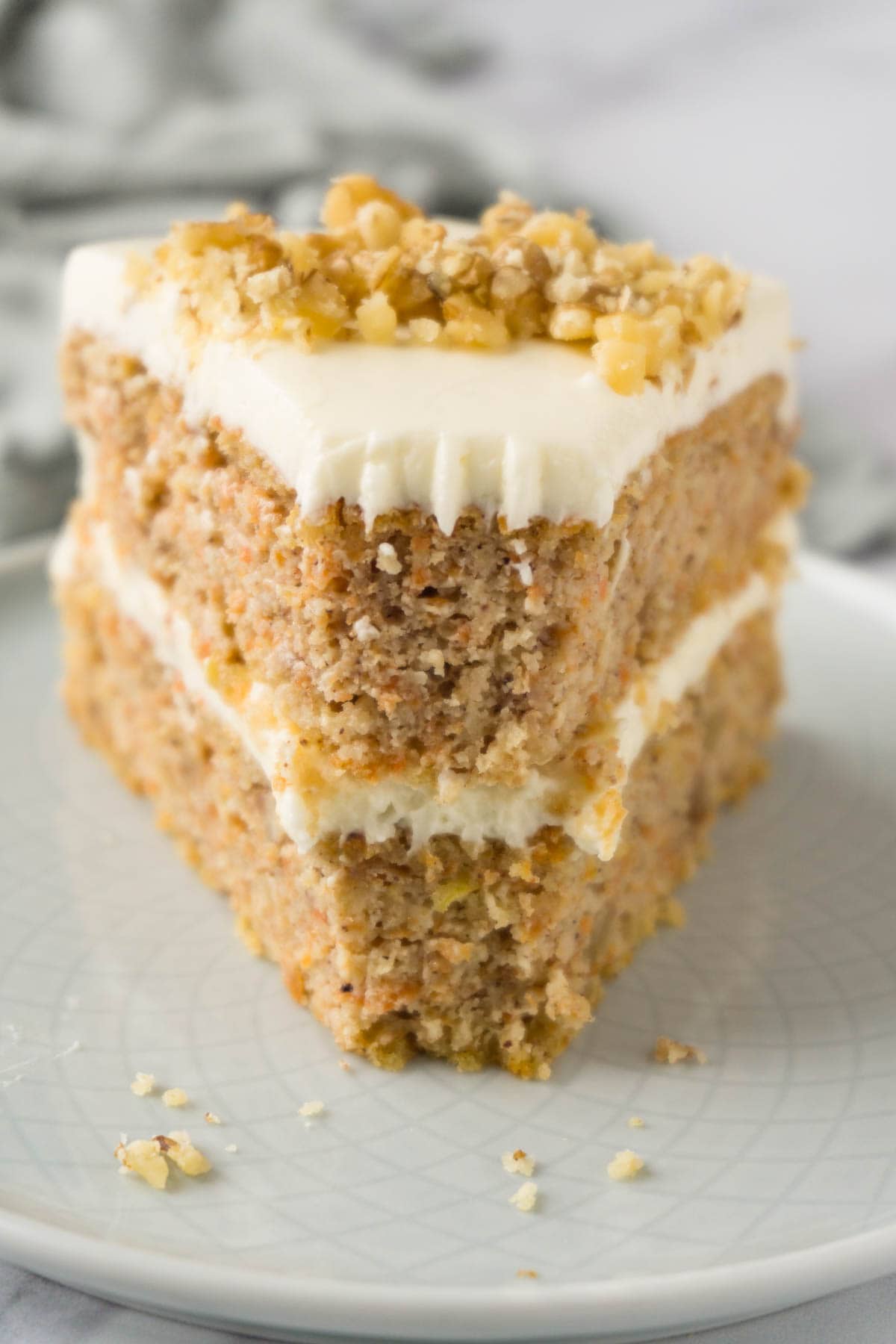 A piece of gluten-free carrot cake topped with walnuts, one bite taken.