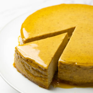 Freshly made pumpkin cheesecake topped with salted caramel, one piece cut out but not taken.