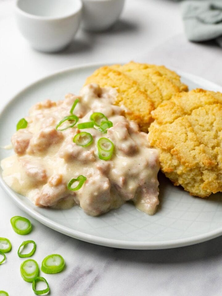 Two biscuits and sausage gravy served on a small round plate.