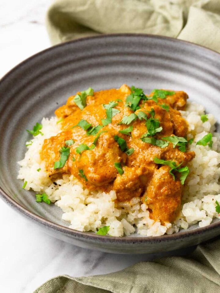 A bowl with butter chicken served over cauliflower rice.