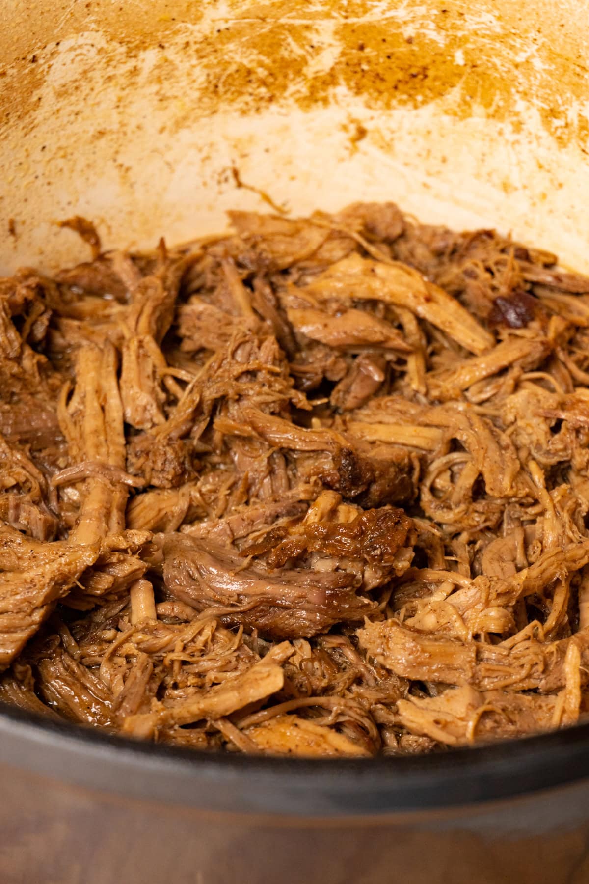 A Dutch oven fileld with juicy pulled pork.