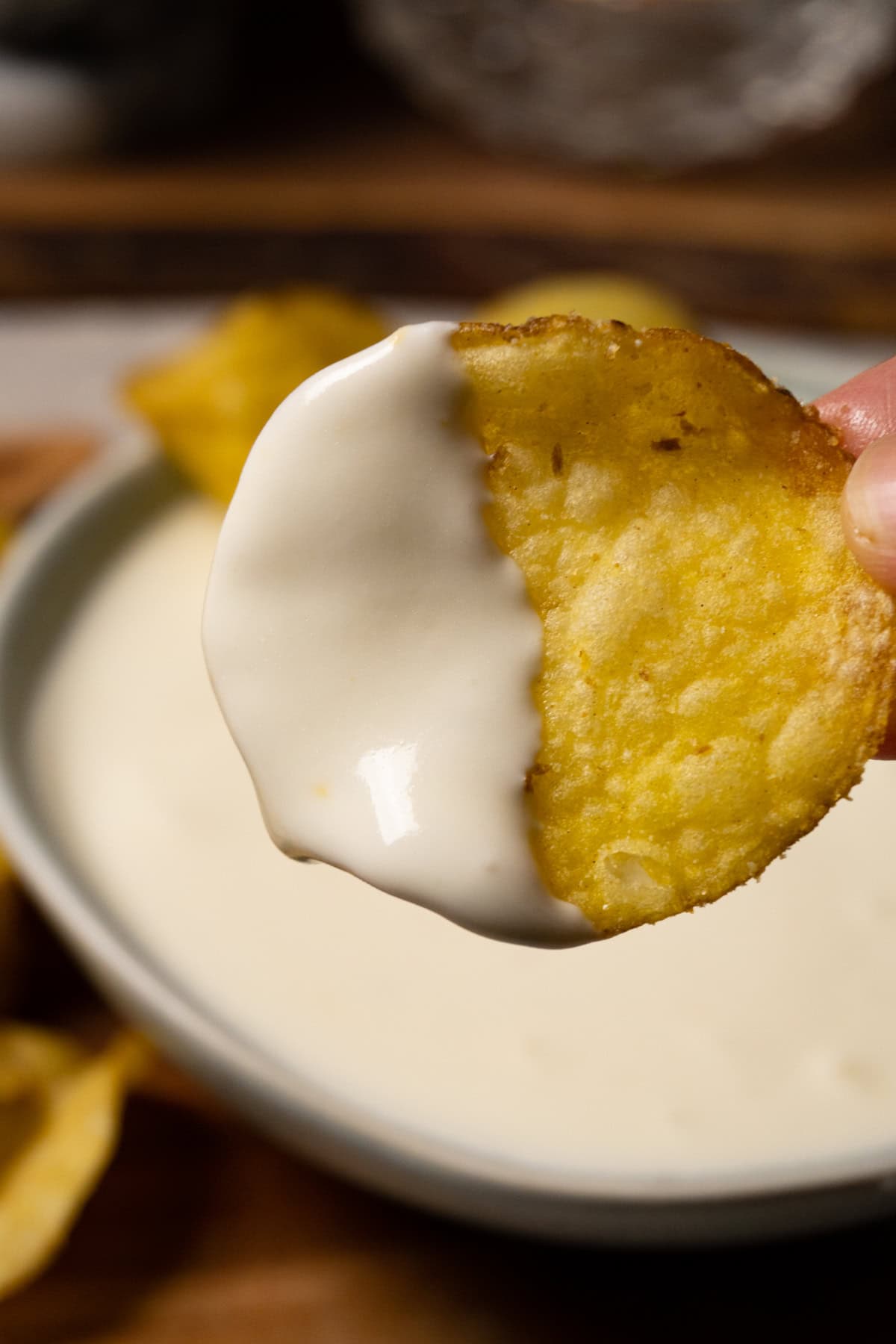 A potato chip half covered in white dipping sauce.