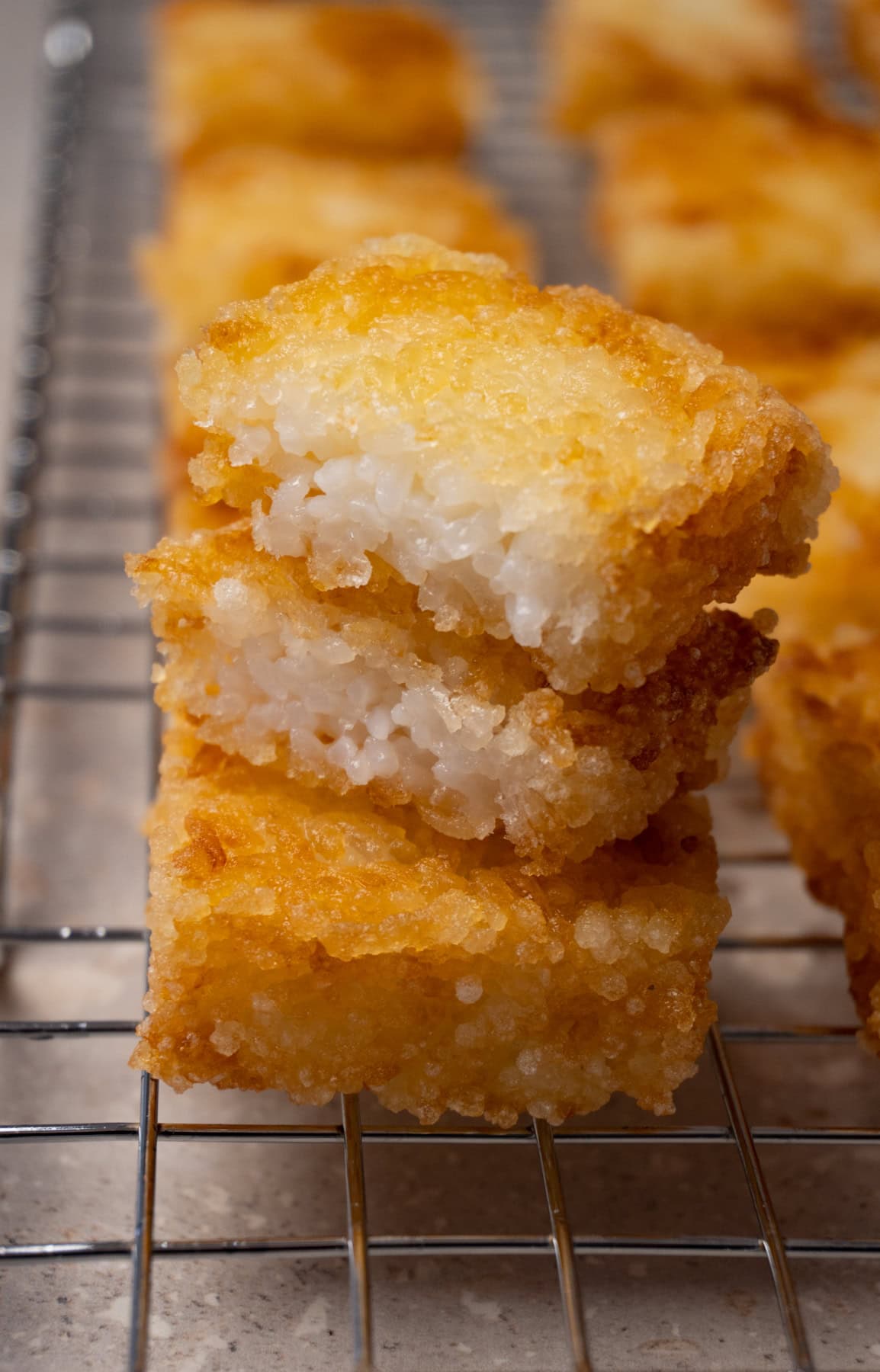 Deep-fried rice cakes on a cooling rack. One cake has been cut in half.